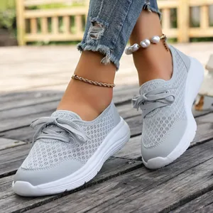 Close-up of grey breathable mesh slip-on sneakers for women on a rustic wooden deck.