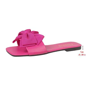 Side view of fuchsia pink flat slide sandal with oversized bow and 1cm heel height detail