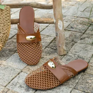 Close-up of breathable brown mesh flat mules with gold oval metal buckle detail