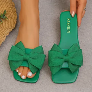 Detailed close-up view of green summer flat sandals featuring a large decorative bow knot