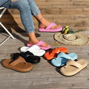 Sandalias de plataforma tipo chanclas para mujer en varios colores en una terraza de madera.