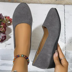 Detailed macro shot of grey suede pointed-toe wedge shoes for women being worn outdoors