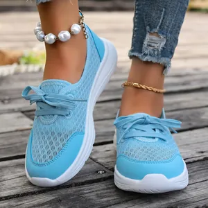 Detail view of light blue mesh slip-on walking shoes for women on a rustic wood floor
