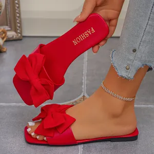Close-up of red flat sandals featuring a large bow and gold 'FASHION' insole logo.