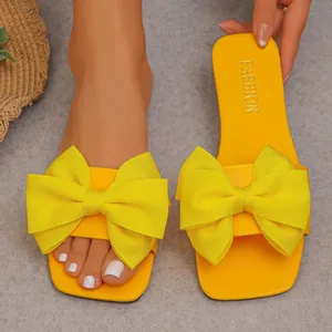 Detailed macro shot of vibrant yellow flat slide sandals with a large oversized bow