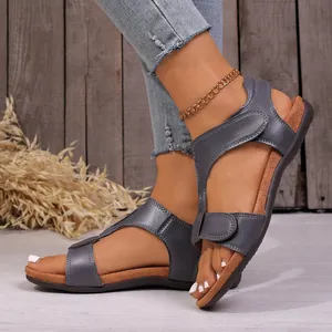 Close-up shot of grey leather wedge sandals featuring adjustable hook-and-loop straps.