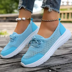 Detailed close-up view of breathable light blue mesh walking shoes on model's feet.