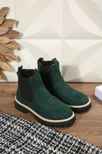 Primo piano di eleganti stivaletti Chelsea in pelle scamosciata verde bosco con suola spessa