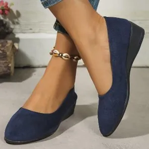 Detailed view of navy blue suede pointed-toe wedge shoes worn with a shell anklet