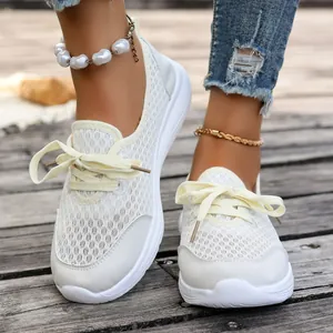 Close-up detail of cream white breathable mesh slip-on walking shoes with flat soles.