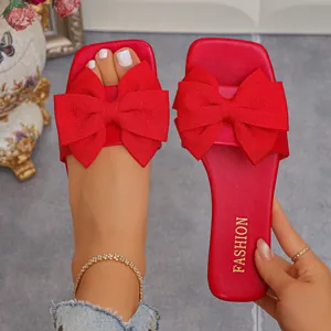 Chic red flat slide sandals featuring a large oversized bow design for summer fashion