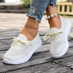 Detailed view of white breathable mesh slip-on sneakers for women worn on wooden path