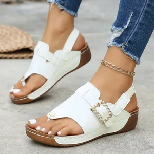 Detailed view of white wedge platform sandals with sparkling buckle and stitching.