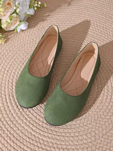 Dettaglio delle ballerine in camoscio verde a punta quadra su tappeto intrecciato
