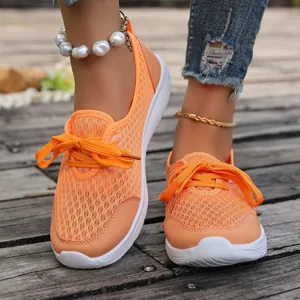 Close-up of vibrant orange mesh walking shoes with white soles on wooden floor