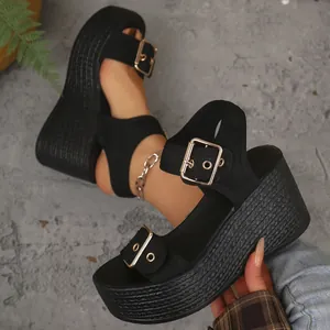 Close-up of black platform wedge sandals with straw woven sole and gold buckles