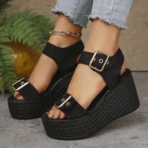Close-up of women's black espadrille wedge sandals with gold buckles and straw sole
