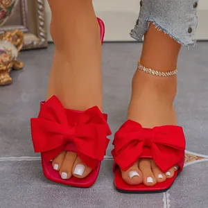 Macro view of elegant women's red flat sandals with a large decorative textile bow