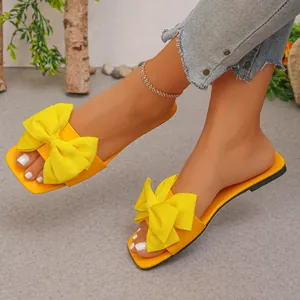 Detailed side view of vibrant yellow summer flat sandals with an oversized bow