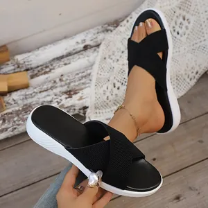 Detail view of women's black criss-cross platform slides shown on a foot and held