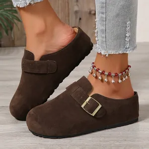 Close-up of brown suede platform clogs with buckle strap worn on feet