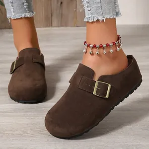 Close-up detail view of brown suede platform clogs featuring an adjustable vintage metal buckle