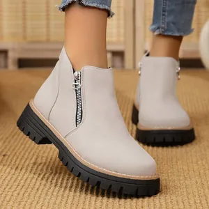 Close-up of light grey suede ankle boots with side zipper and thick lug sole