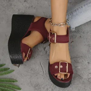 Close-up detail of stylish burgundy wedge platform sandals with gold buckle straps