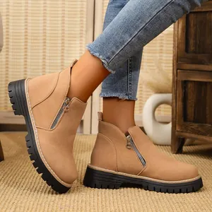 Side view of tan suede round-toe ankle boots with side zippers and chunky black soles.