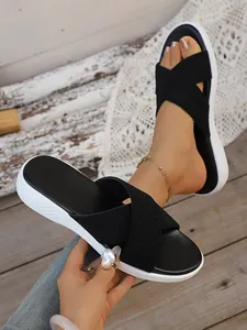 Detail view of black cross-strap platform sandals worn on foot and held by hand