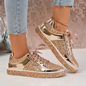 Detailed shot of sparkling gold glitter sneakers with metallic panels and ribbons.