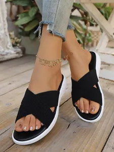 Stylish close-up of black cross-strap platform sandals for women on a wooden deck