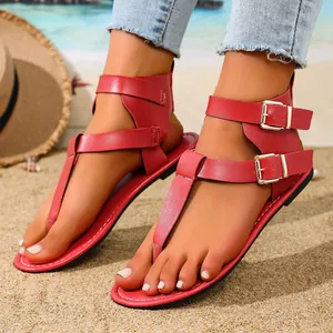 Detailansicht der roten flachen Zehentrenner-Sandalen mit eleganten Metallschnallen