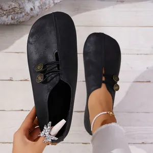Detail of black matte flat loafers featuring decorative side buttons and round toe