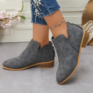 Détail de bottines grises élégantes à talons épais avec une fermeture éclair à l'arrière.
