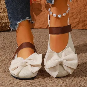 Detalle de zapatos planos beige con lazo grande y correa de velcro marrón