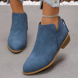 Détail de bottines en daim bleu avec bout pointu et talon épais en bois texturé