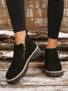 Close-up view of black suede ankle boots featuring a side zipper and durable lug sole detail