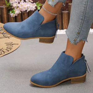 Gros plan de bottines en daim bleu pour femme avec bout pointu, zip arrière et talon épais