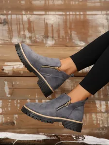 Grey suede ankle boots with side zipper and thick lug sole on wooden background