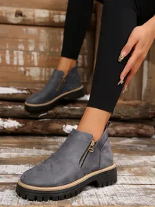 Close-up of grey faux suede ankle boots with gold side zipper and thick lug sole.