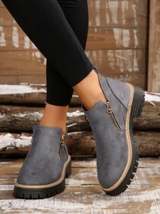 Detailed macro view of grey faux suede ankle boots with golden zipper and lug sole
