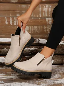 Detailed view of women's beige suede Martin boots featuring side zippers and thick black soles.