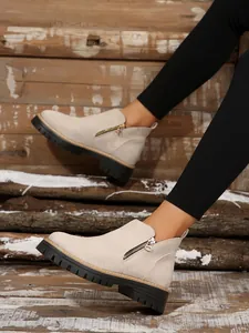 Close-up of beige suede ankle boots with side zipper and thick lug sole