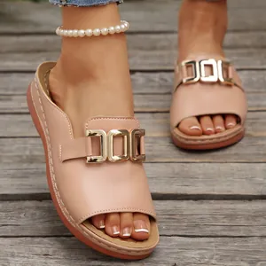 Detailed view of women's wedge slides featuring gold metal buckles on soft pink leather