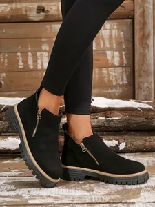 Detail of black round-toe ankle boots with side zipper and chunky sole for women.