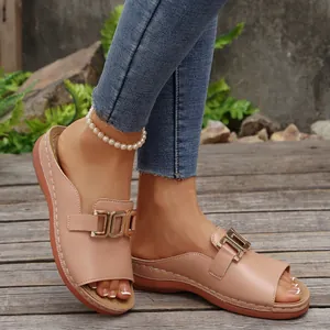 Detail view of nude wedge peep-toe sandals with metallic buckle on wooden deck