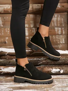 Black suede ankle boots with side zipper and thick lug sole shown on model in winter setting