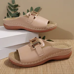 Close-up of beige wedge sandals for women with elegant golden metallic buckle detail.