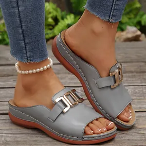 Close-up of women's blue-grey wedge slide sandals with decorative gold metal buckle